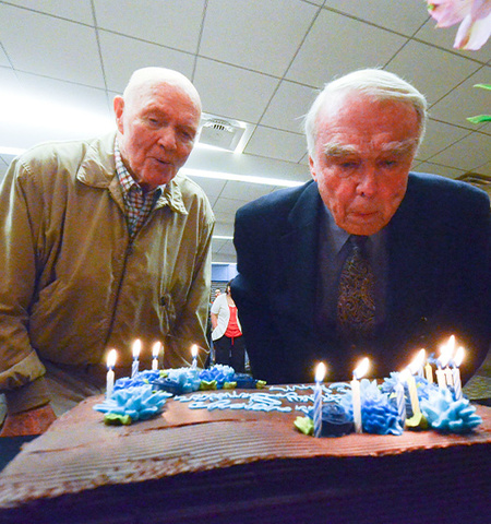 Sen. John Glenn, left, and Faculty Emeritus Doug Jones blow out candles on the cake for the senator’s 94th birthday celebration in Page Hall at the John Glenn College of Public Affairs.