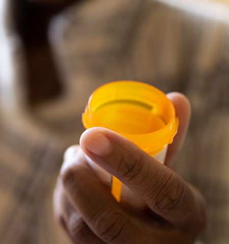 a close-up photo of a hand holding an open prescription medication bottle (Credit: Getty Images)