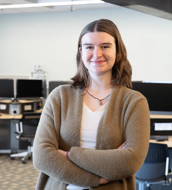 A female student wearing a brown sweater and smiling.