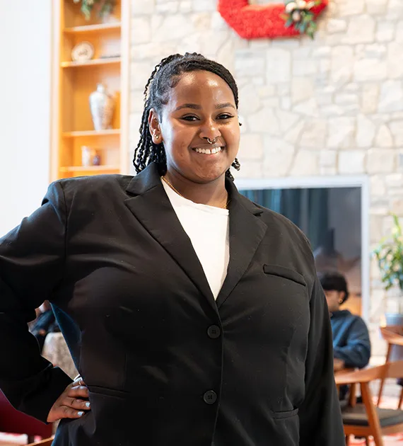 A female student wearing a black blazer and white shirt smiling.