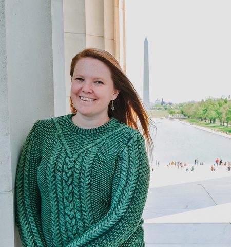 Katy Hogan in green sweater standing with Washington Monument in background