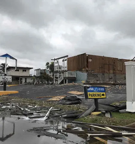 storm debris and a damaged building under a cloudy sky in Rockport, TX, following Hurricane Harvey in 2017