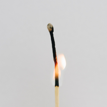 a lit match in front of a gray background