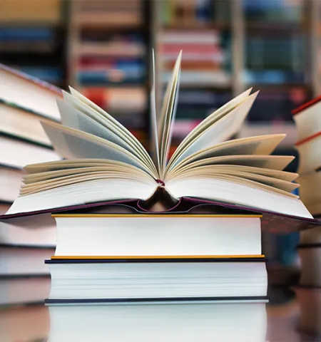 Three stacks of books and the top book on the middle stack opening.