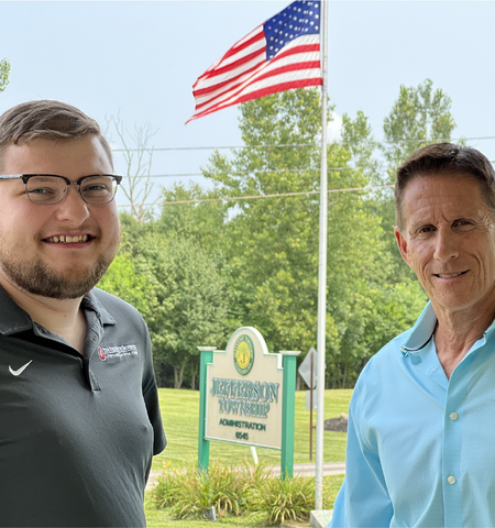 Glenn College Master of Arts in Public Policy and Management graduate Guy Worley, left, and student Joe Laborie stand outside on a porch with an American flag in the background