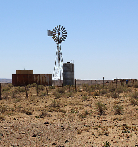 A windmill and water pumps in Navajo Nation with blue sky and dry terrain