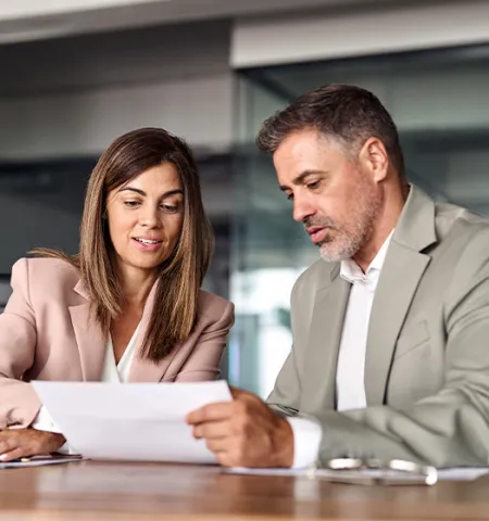 Two professional executives discussing papers and working together in an office (AdobeStock.com).