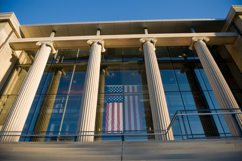 Exterior of a building with stone columns and an American flag
