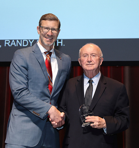 John Glenn College of Public Affairs Dean Trevor Brown presents the college’s Outstanding Public Service Award to Ohio State Vice Provost for Academic Programs W. Randy Smith on a stage at the Spring Pre-Commencement Ceremony.