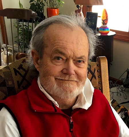 Glenn College Emeritus Professor Charles Adams sitting in a chair in a home