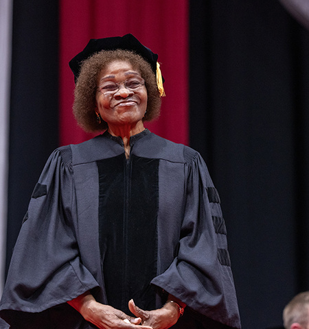 Elizabeth Lwanga King stands on stage in academic regalia before she receives an Honorary Doctor of Public Service degree at The Ohio State University.