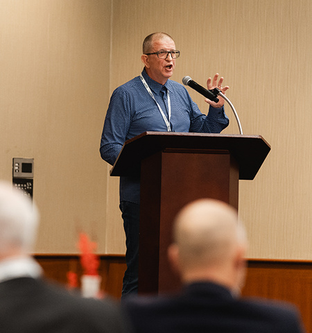 Clifford Stott, a Glenn College visiting faculty member and crowd behavior expert, stands on a podium and shares his knowledge of police-community dialogue with Strong Cities Network participants. (Photo Credit: Joss Ford/Jake Olson Photography)