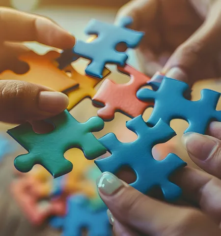 Hands connecting jigsaw pieces, signifying the joining of different skills and expertise