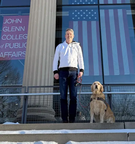 John Glenn College of Public Affairs graduate Ryan Brownfield and his dog, Mable, stand on the steps in front of Page Hall.