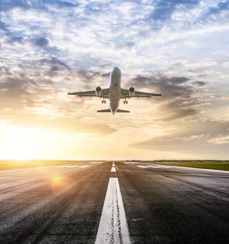 a commercial jet takes off from a runway with the sun and clouds in the background