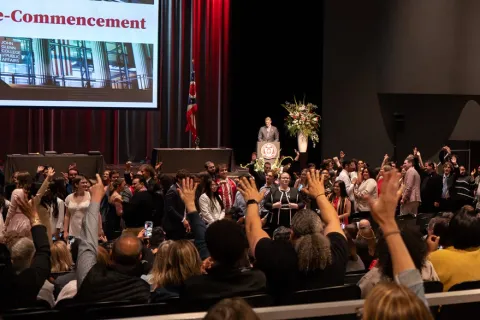 Dean Trevor Brown stands on stage at the Glenn College precommencement event