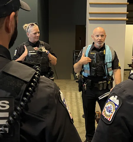 Columbus Police Sgt. Steve Dyer, center, in blue vest, stands in a circle with other police officers to discuss preparations for the Pride March in 2024.
