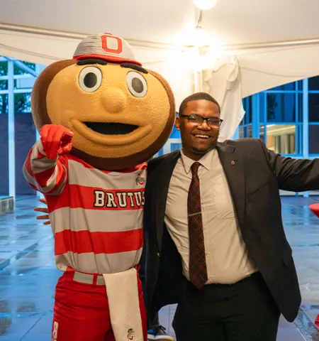 Ohio State’s Brutus Buckeye and Glenn College student Ejuan Kendrick celebrate under a party tent.