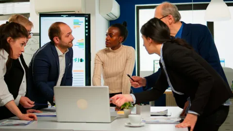 International business team talking to woman mentor discussing company development plan standing at broadroom