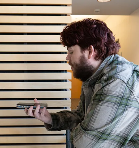 John Glenn College of Public Affairs Doctoral candidate Brandon Frye speaks into a cell phone while using AI tools