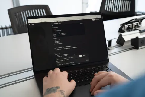 two hands on a computer keyboard with a ChatGPT discussion on the monitor