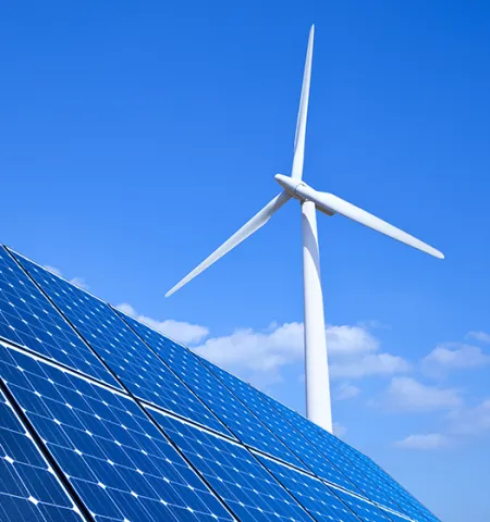 Solar panels and a wind turbine with a blue sky and clouds in the background