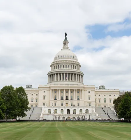 U.S. Capitol Building with clouds and blue sky in the background and grass in the foreground