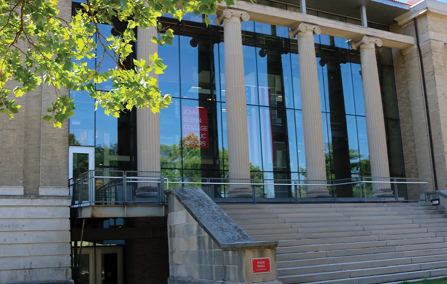 A green tree next to the front steps of Page Hall.