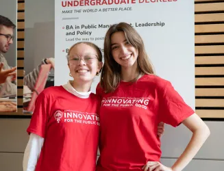 Two girls pose in red shirts. They are smiling.